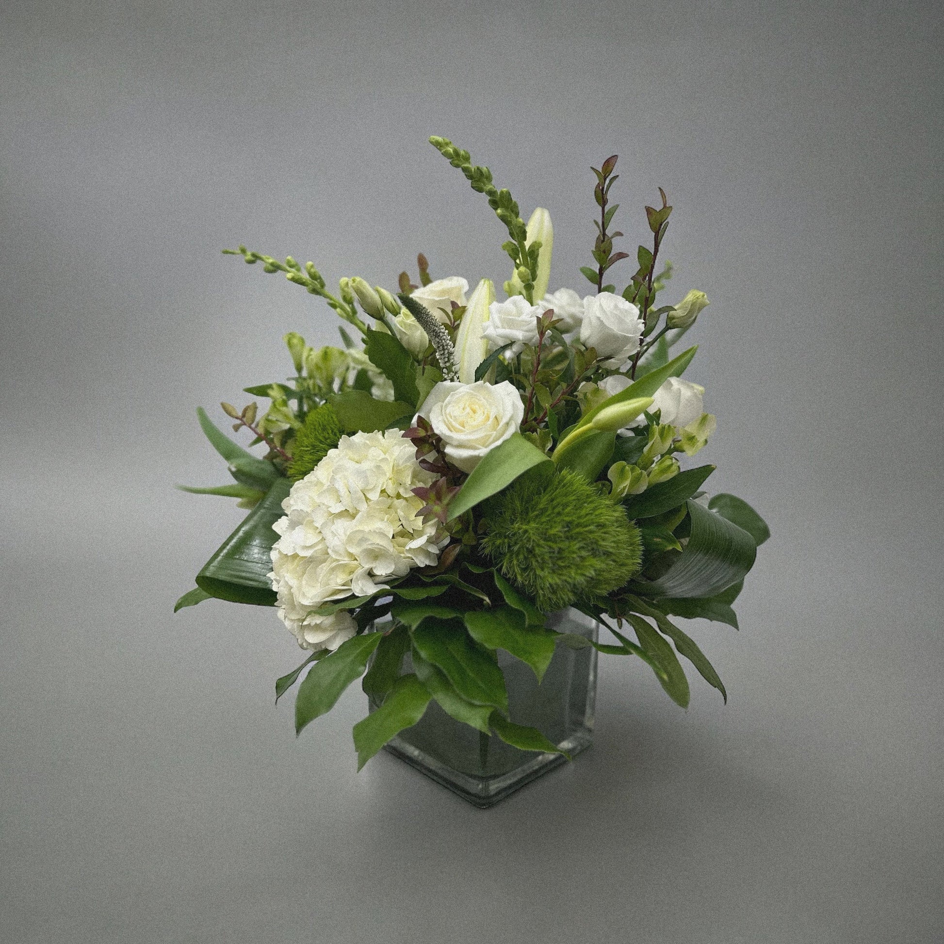 Luxury white floral arrangement with hydrangeas, roses, and lilies in a glass vase. Perfect for any occasion, best florist in Toronto.