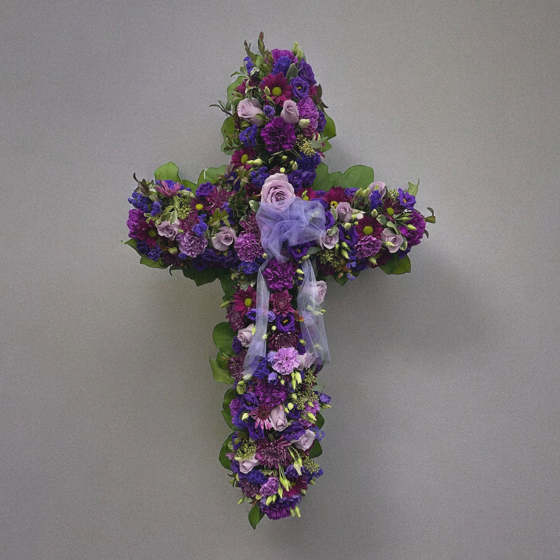 Elegant Purple Cross funeral floral arrangement with lavender flowers, symbolizing peace and spirituality. Best sympathy wreath, Toronto delivery.