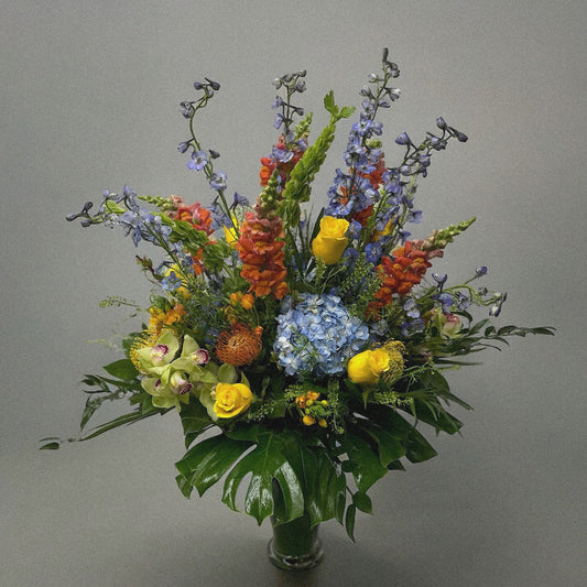 Luxury floral arrangement with lavender delphiniums, vibrant blooms, and monstera leaves. Best flower shop in Toronto, same-day delivery.