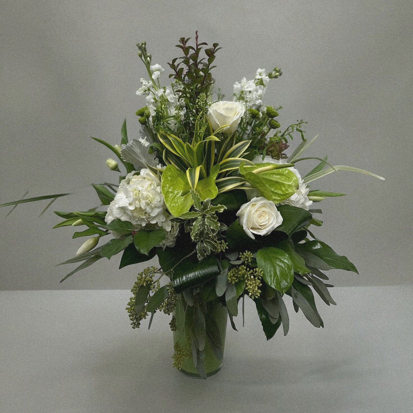 Elegant Serene Grace floral arrangement with white roses, hydrangeas, and anthuriums in a glass vase, perfect for all occasions. Best florist in Toronto, GTA.
